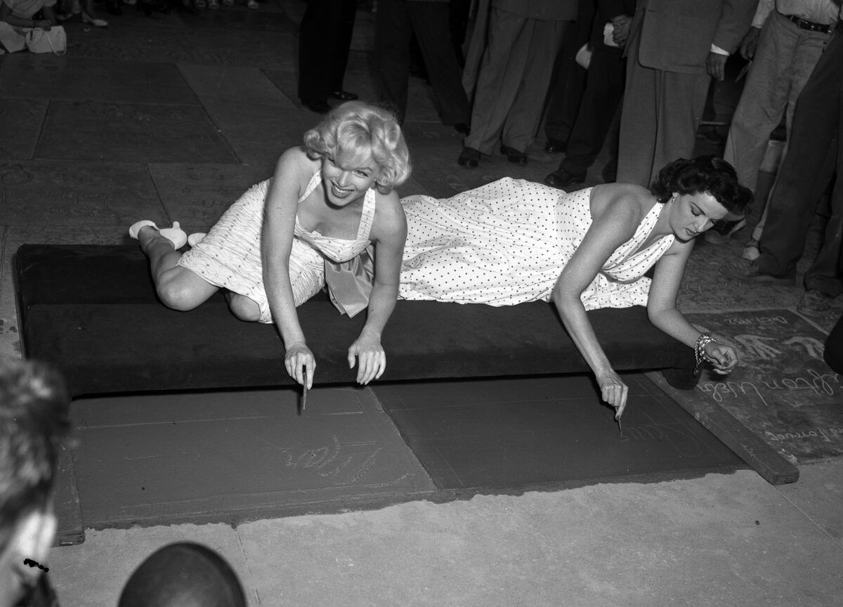 Marilyn Monroe and Jane Russell kneeling to write in wet cement at Grauman’s Chinese Theatre in 1953