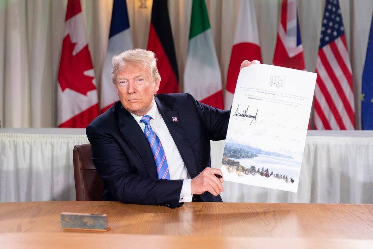 Donald Trump displaying his signature on the G7 scroll in Charlevoix